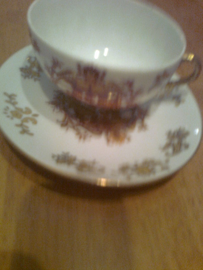 Красивая фарфоровая чашка с блюдцем в коричнево-золотистых тонах